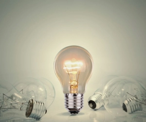 Image of a lit light bulb standing out from the rest of the bulbs