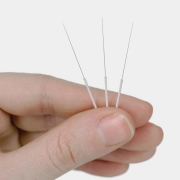 A close up shot of a hand holding acupuncture needles